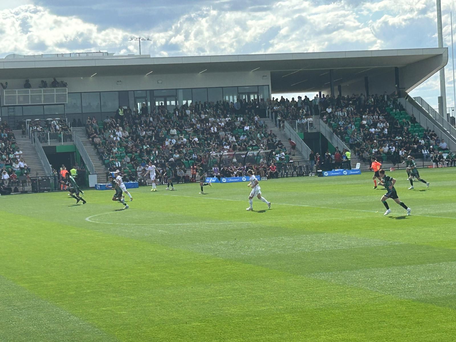 Football match in front of a full green-seated stand